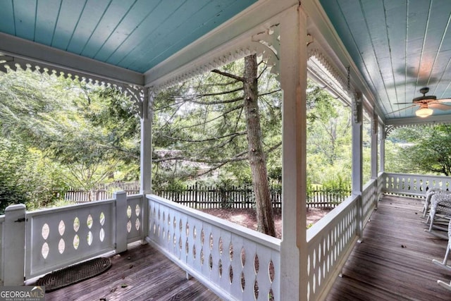 wooden terrace featuring ceiling fan, covered porch, and fence