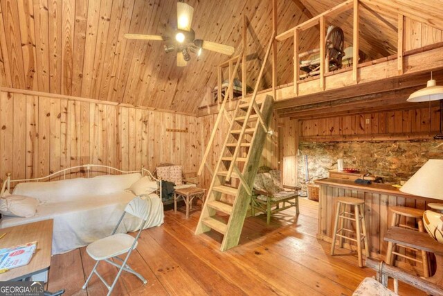 bedroom with high vaulted ceiling, wood-type flooring, wooden walls, and wood ceiling