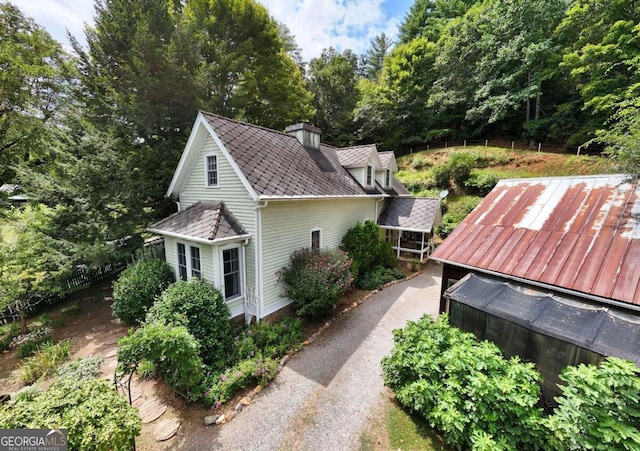 view of side of home with a shingled roof and a chimney