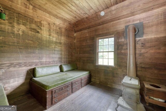 interior space featuring wood walls, hardwood / wood-style flooring, wooden ceiling, and a wood stove