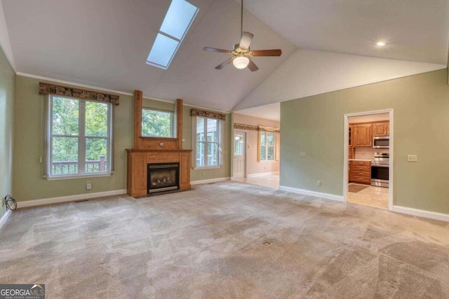 unfurnished living room featuring light colored carpet, a skylight, and a wealth of natural light