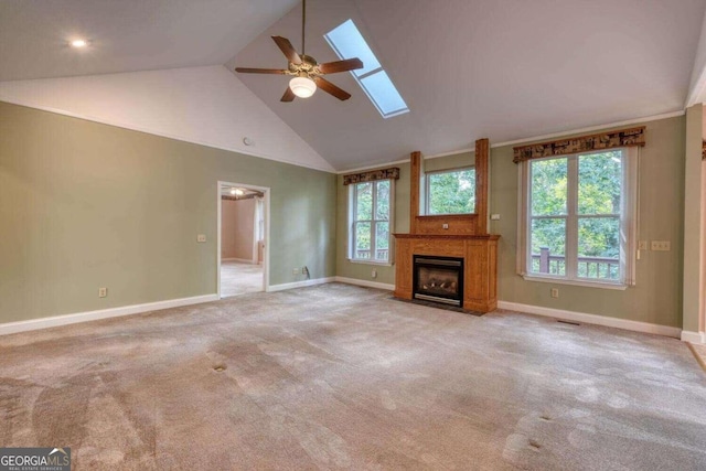 unfurnished living room featuring high vaulted ceiling, ceiling fan, a skylight, and light colored carpet