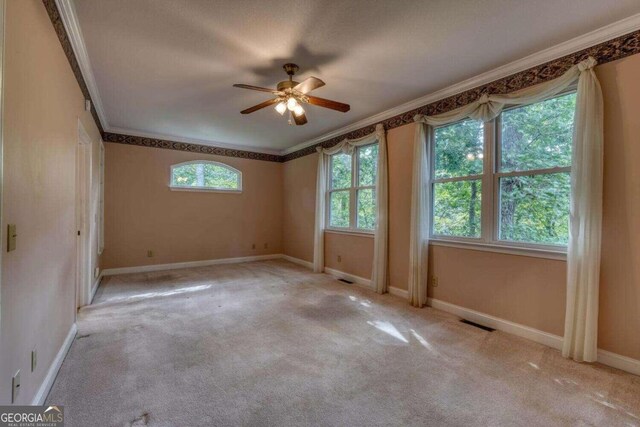 unfurnished room with ceiling fan, crown molding, and light carpet