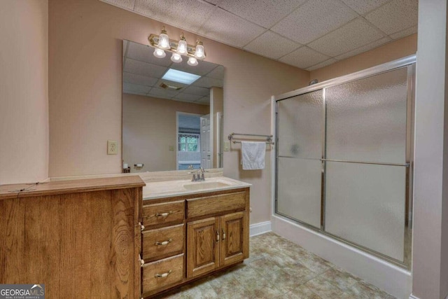 bathroom featuring tile patterned flooring, vanity, a paneled ceiling, and a shower with shower door