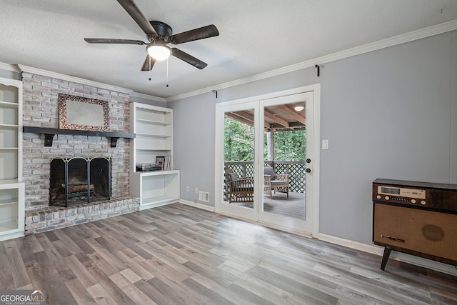 unfurnished living room featuring ceiling fan, a brick fireplace, hardwood / wood-style flooring, a textured ceiling, and crown molding