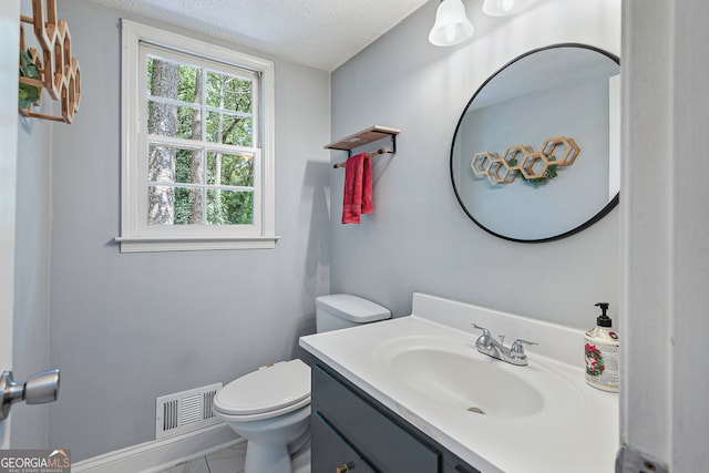 bathroom featuring tile patterned floors, toilet, a textured ceiling, and vanity