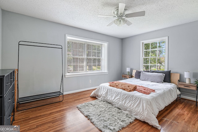 bedroom featuring ceiling fan, dark wood-type flooring, and a textured ceiling