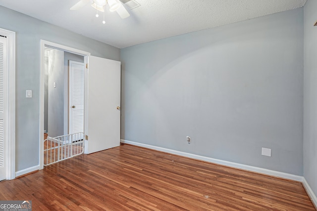 unfurnished bedroom with ceiling fan, a closet, a textured ceiling, and hardwood / wood-style floors