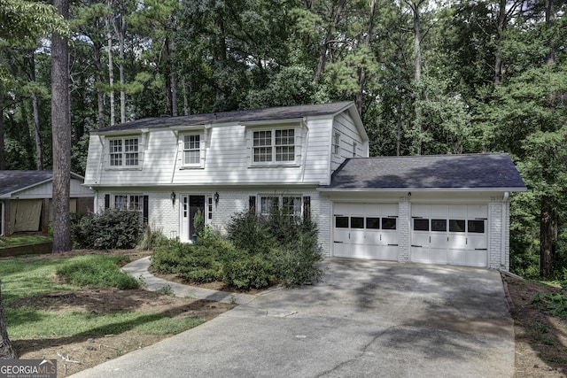 colonial inspired home featuring a garage, driveway, and brick siding