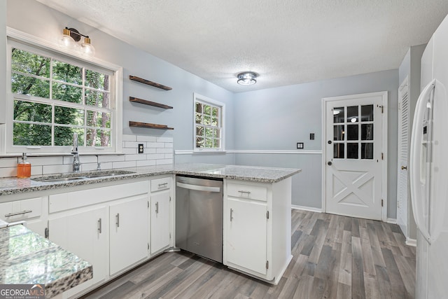 kitchen featuring stainless steel dishwasher, hardwood / wood-style flooring, kitchen peninsula, and white cabinets