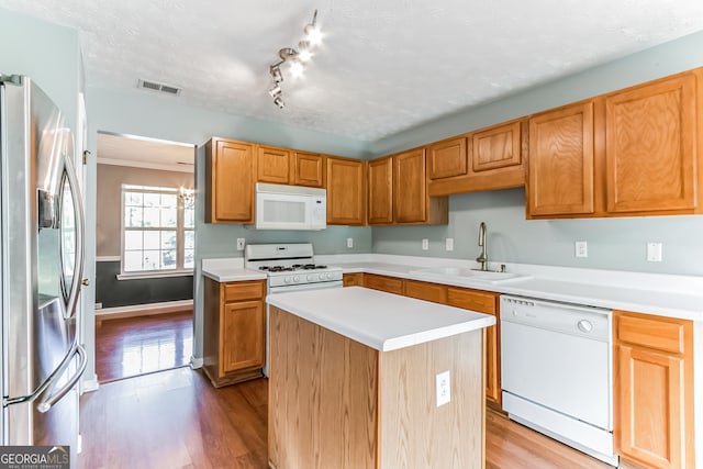 kitchen featuring light hardwood / wood-style floors, sink, a textured ceiling, a center island, and white appliances