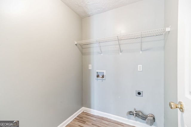 clothes washing area featuring electric dryer hookup, a textured ceiling, hardwood / wood-style floors, and washer hookup