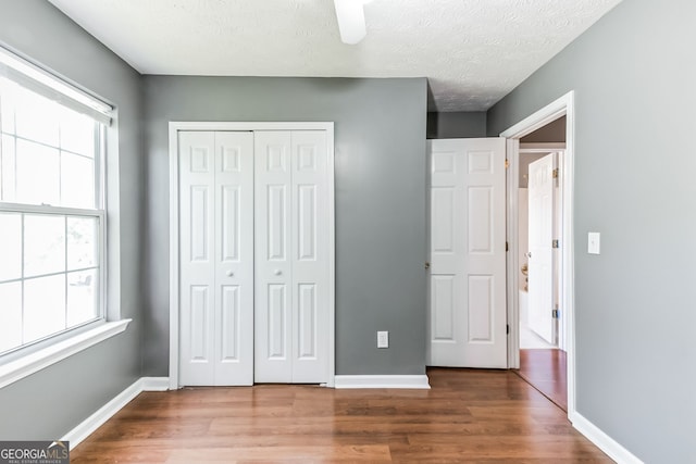 unfurnished bedroom with multiple windows, hardwood / wood-style floors, and ceiling fan