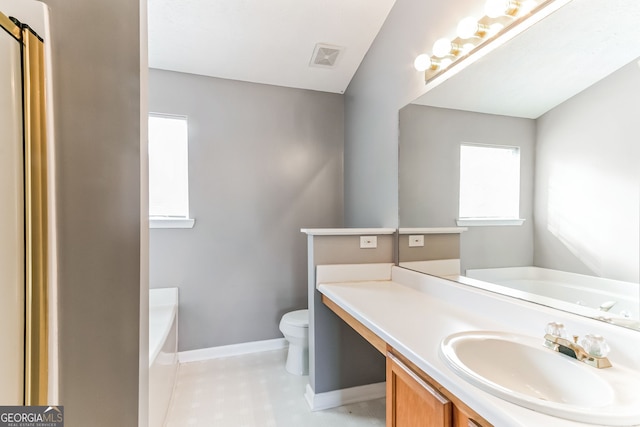 bathroom featuring a washtub, toilet, vanity, and tile patterned floors