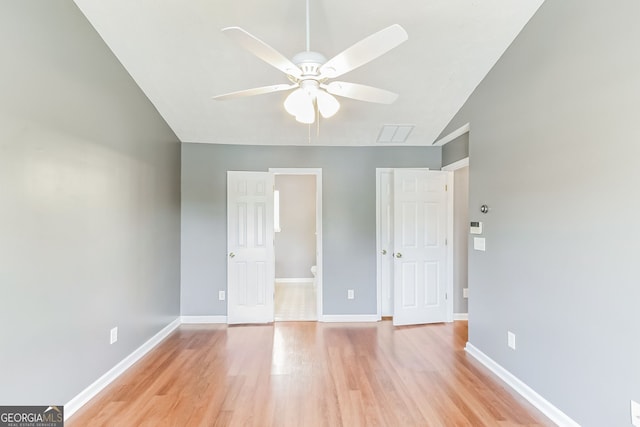 unfurnished bedroom featuring light hardwood / wood-style floors, ensuite bath, ceiling fan, and lofted ceiling