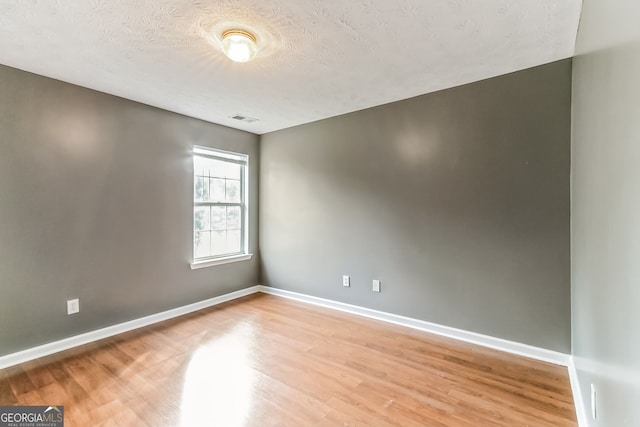 spare room with a textured ceiling and wood-type flooring