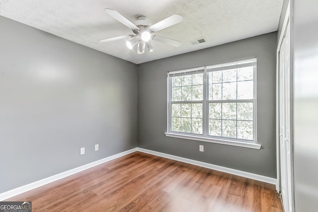 empty room featuring ceiling fan, hardwood / wood-style flooring, and a textured ceiling