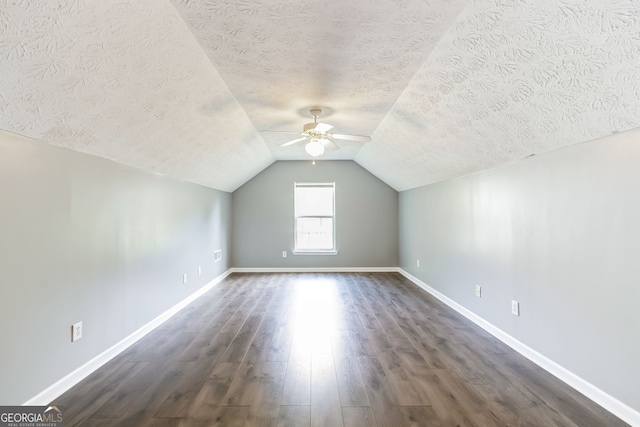 bonus room featuring a textured ceiling, ceiling fan, vaulted ceiling, and dark hardwood / wood-style floors