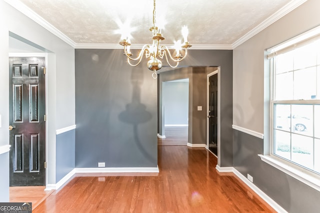 unfurnished dining area featuring hardwood / wood-style flooring, a notable chandelier, and ornamental molding