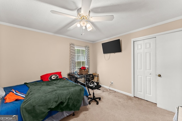 carpeted bedroom with a textured ceiling, a closet, ceiling fan, and crown molding