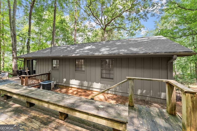 rear view of house featuring central air condition unit, board and batten siding, a deck, and a shingled roof