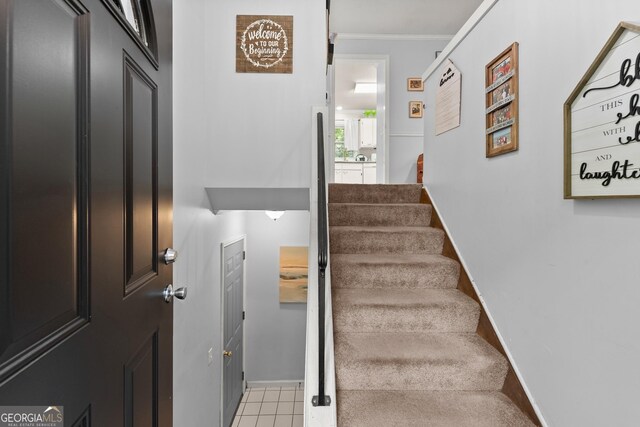 stairs with ornamental molding and tile patterned flooring