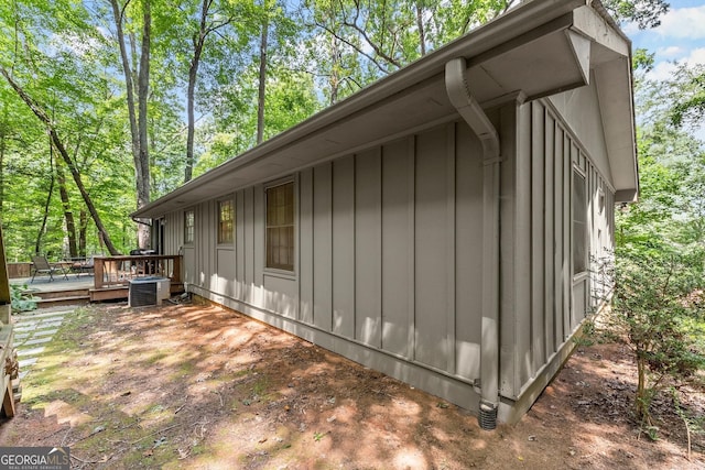 view of property exterior with board and batten siding, central AC, and a wooden deck