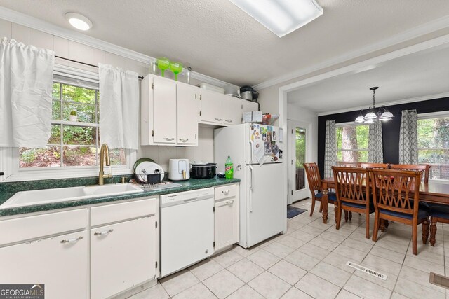 kitchen featuring white appliances, a notable chandelier, a healthy amount of sunlight, and white cabinetry