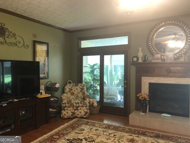 living room featuring a tiled fireplace, crown molding, and dark hardwood / wood-style floors