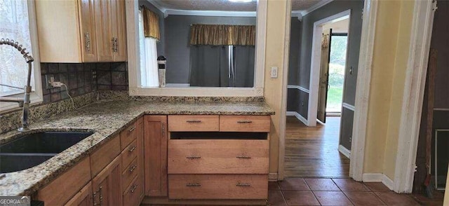 kitchen featuring a wealth of natural light, dark wood-type flooring, ornamental molding, and stone counters