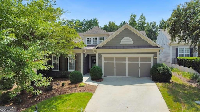 view of front of house with an attached garage, driveway, metal roof, and a standing seam roof