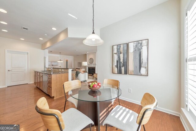 kitchen featuring light hardwood / wood-style flooring, stainless steel appliances, sink, dark stone counters, and tasteful backsplash