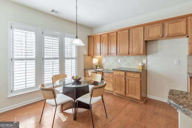 kitchen with light wood-type flooring, a kitchen island with sink, decorative light fixtures, sink, and appliances with stainless steel finishes