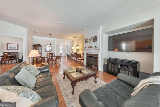 living room featuring a chandelier, light hardwood / wood-style floors, and a high end fireplace