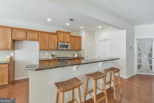 kitchen with baseboards, wood finished floors, visible vents, and stainless steel appliances