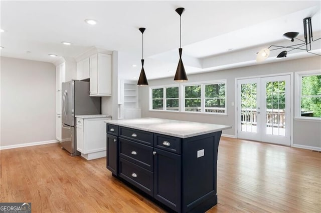 kitchen featuring a kitchen island, white cabinetry, light wood-type flooring, and stainless steel refrigerator