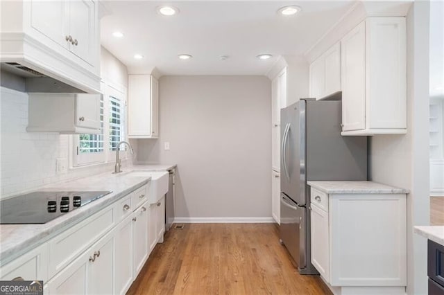 kitchen featuring decorative backsplash, light hardwood / wood-style flooring, white cabinetry, and black electric cooktop