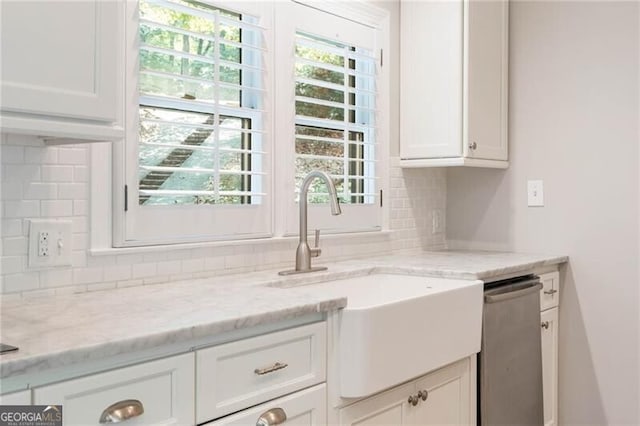 kitchen featuring white cabinets, light stone counters, backsplash, and dishwasher