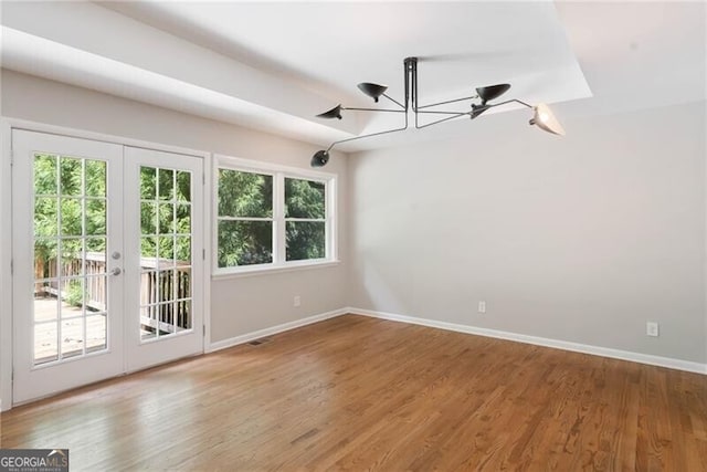 spare room with an inviting chandelier, french doors, and hardwood / wood-style floors