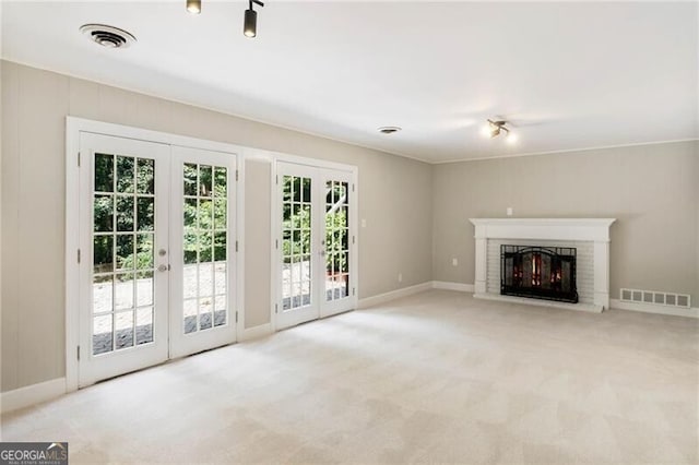 unfurnished living room with a fireplace, light colored carpet, and french doors