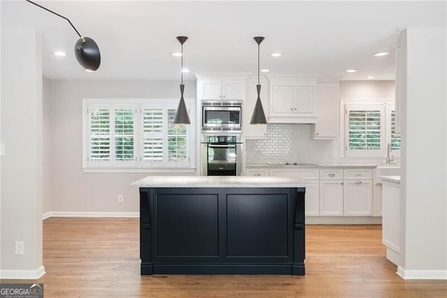 kitchen with backsplash, light hardwood / wood-style floors, white cabinets, and double oven