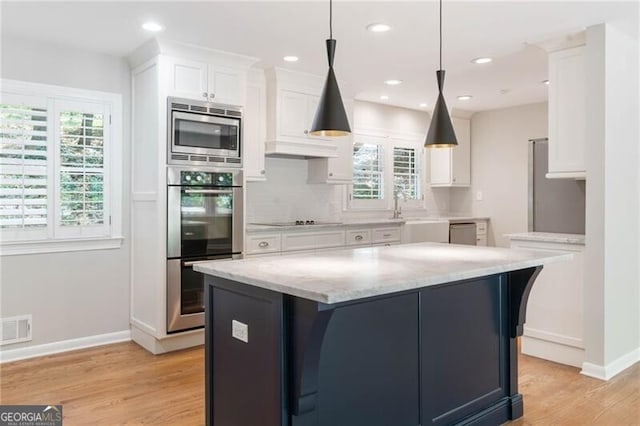 kitchen featuring appliances with stainless steel finishes, light hardwood / wood-style flooring, a healthy amount of sunlight, and tasteful backsplash