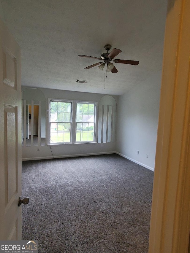 carpeted empty room featuring ceiling fan and a textured ceiling