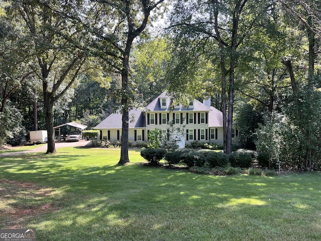 view of front of property with a front yard, a chimney, and a detached carport