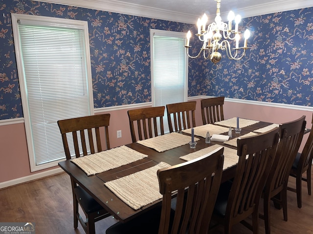 dining room featuring a notable chandelier, crown molding, wood finished floors, and wallpapered walls