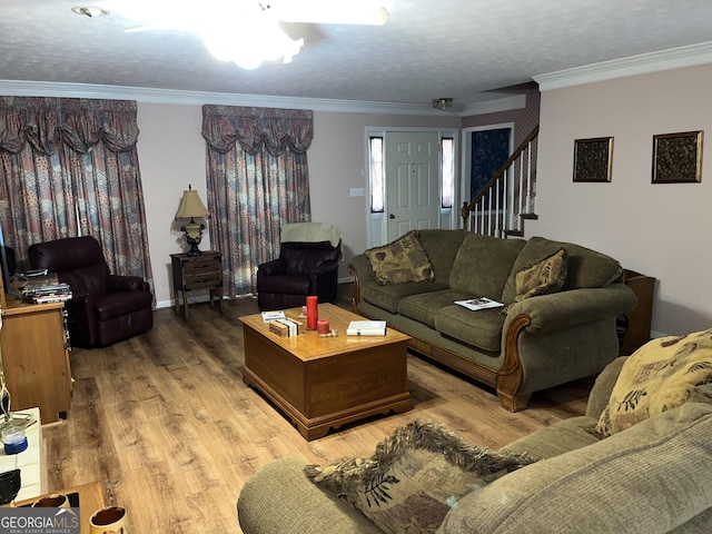 living area with stairs, a textured ceiling, wood finished floors, and crown molding