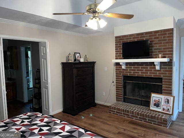 bedroom with a fireplace, crown molding, dark wood-type flooring, ceiling fan, and baseboards