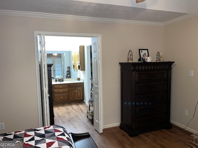 bedroom featuring ornamental molding, light wood finished floors, ensuite bath, and baseboards