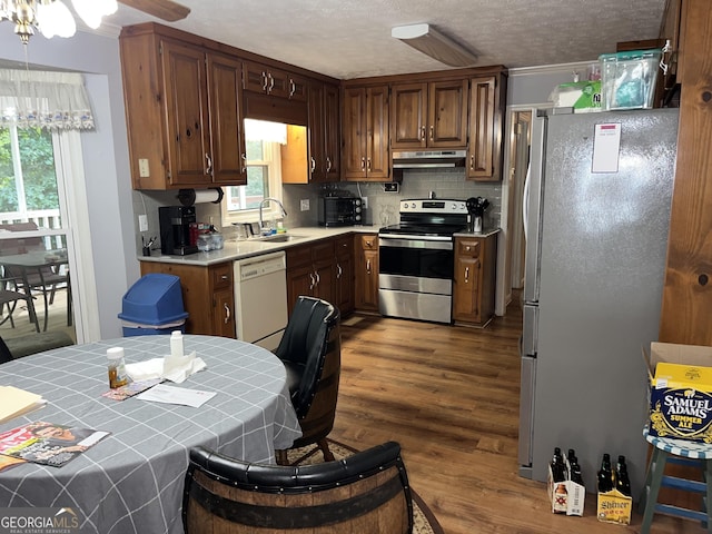 kitchen with stainless steel appliances, tile counters, a wealth of natural light, a sink, and under cabinet range hood