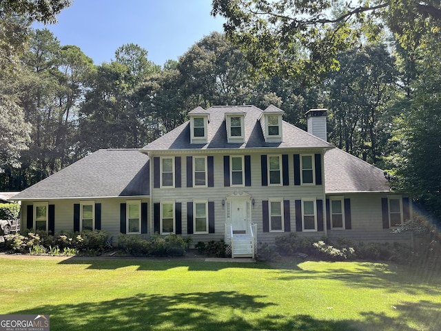 view of front of home featuring entry steps, a shingled roof, and a front lawn